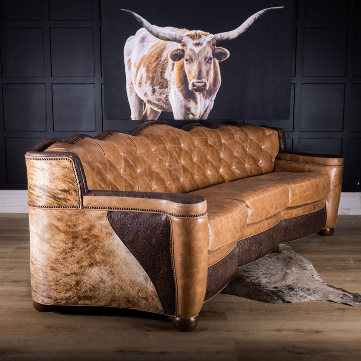 Brown leather sofa in a room with a large cow head painting on the wall.